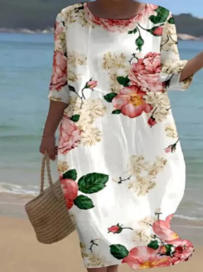 Donna che indossa l’abito floreale elegante Miranda in un ambiente estivo